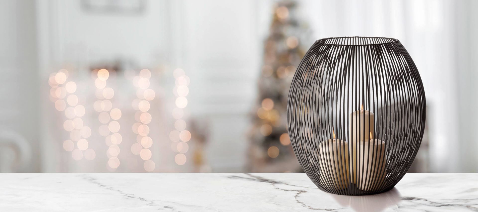 Louisiana Windlicht Philippi XXL aus schwarzem Metalldraht mit brennenden Kerzen auf Marmortisch.