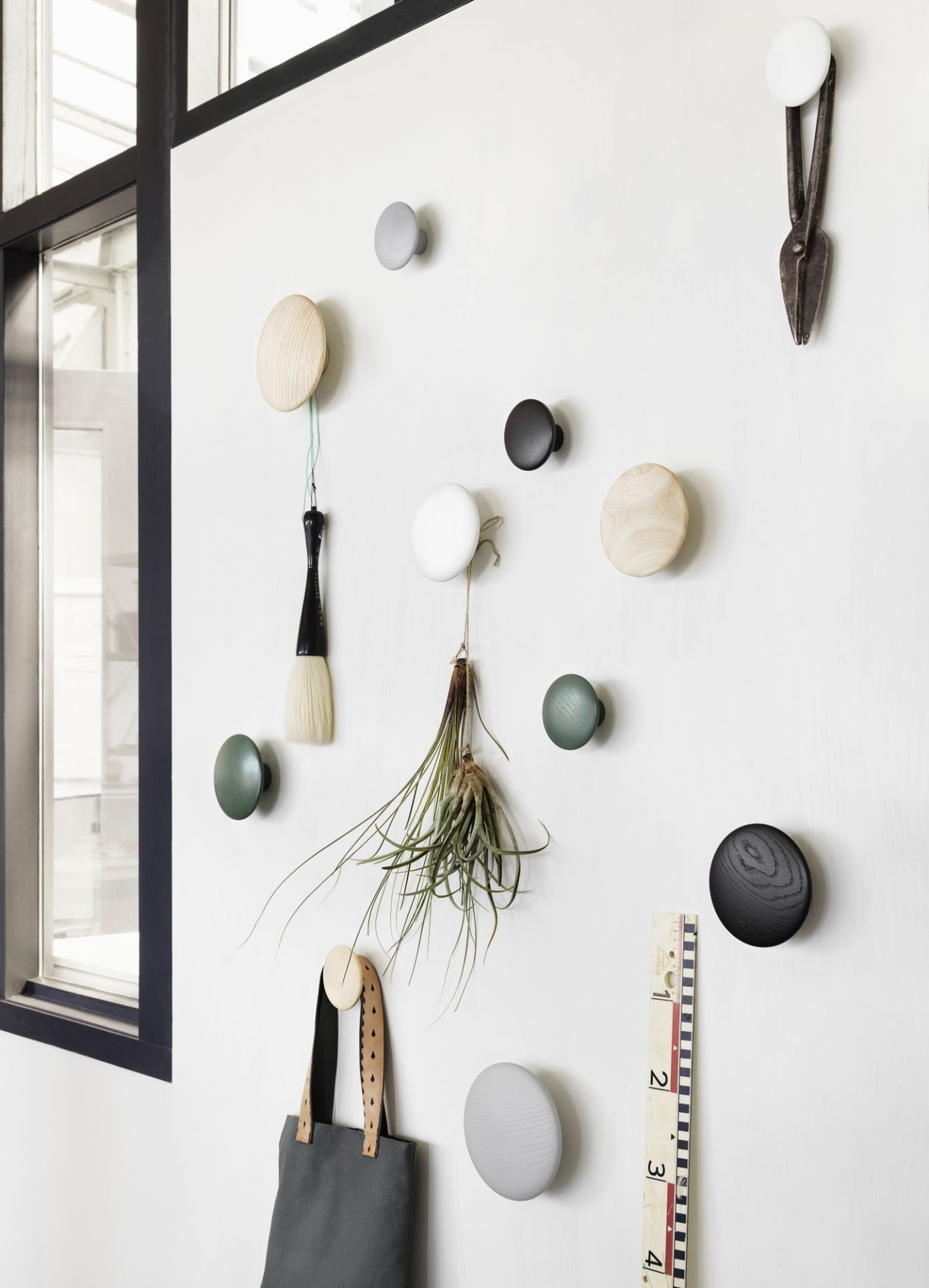The Dots Garderobenhaken 5er Set von Muuto in verschiedenen Farben an einer Wand.