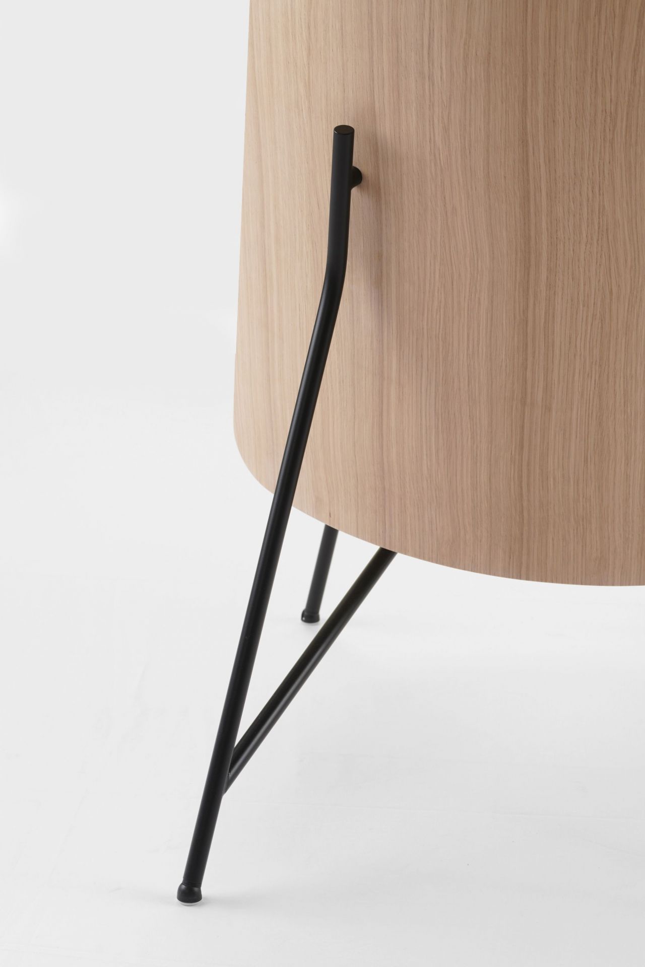 Detailaufnahme des Tinker Sessels von Prostoria mit hellem Holzkorpus und schwarzen Metallbeinen.