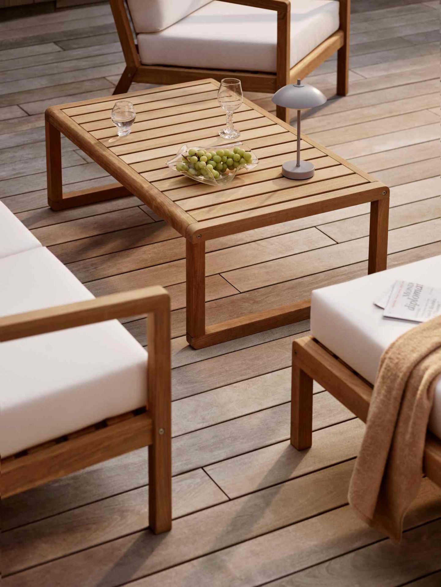 Clam Portable Tischleuchte von Fritz Hansen auf einem Gartentisch mit Getränken und Trauben.