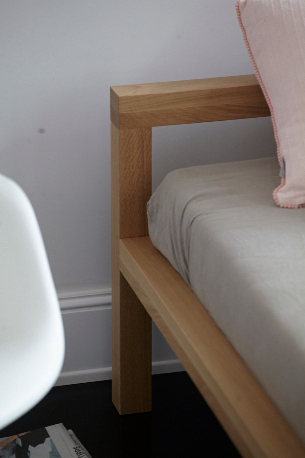 Detailaufnahme vom Pure Bett aus Eiche, 180x200 cm, mit hellem Bettzeug und Kissen.