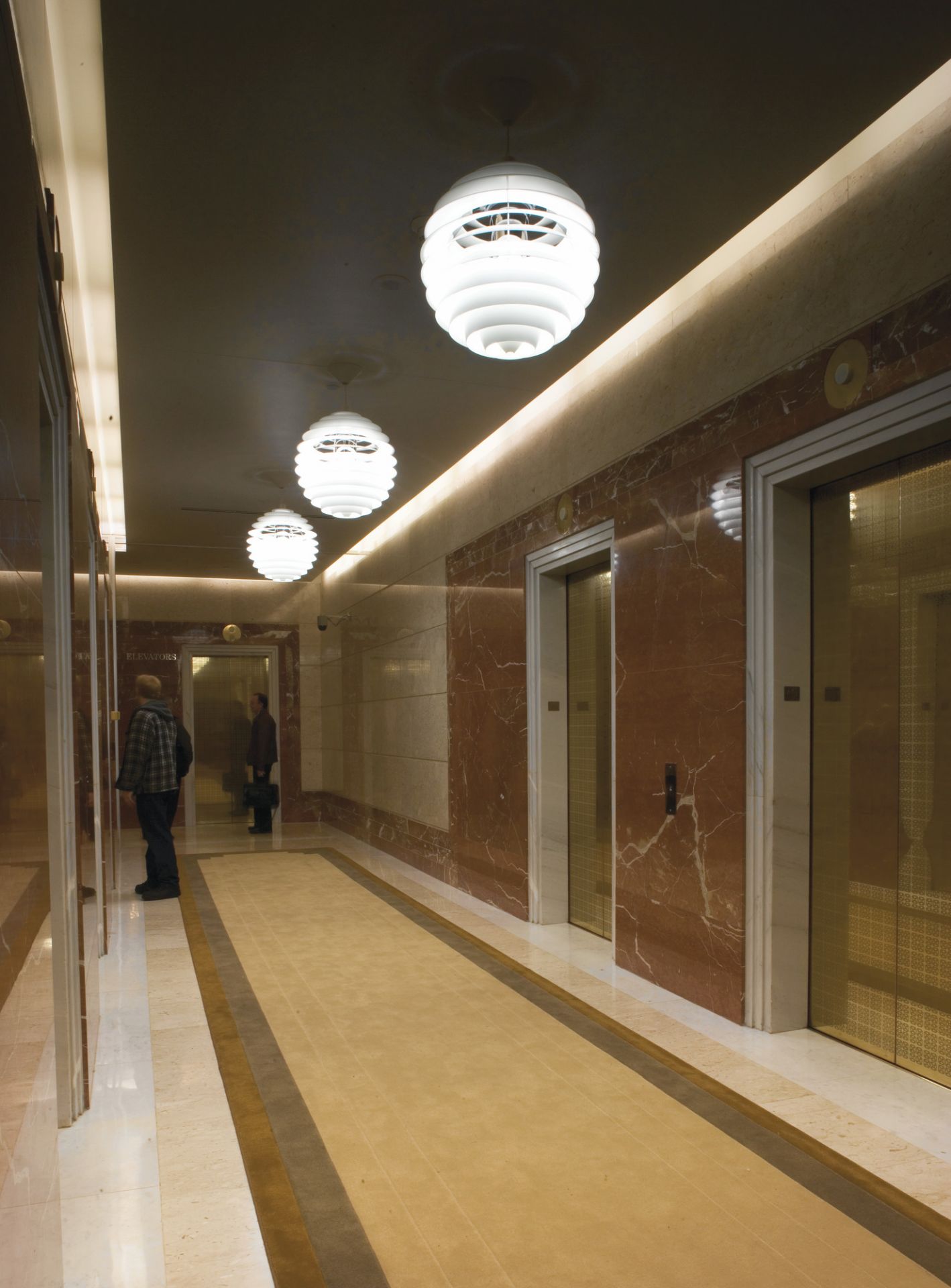 Flur mit drei PH Louvre Pendelleuchten von Louis Poulsen, modernes Design und Beleuchtung.