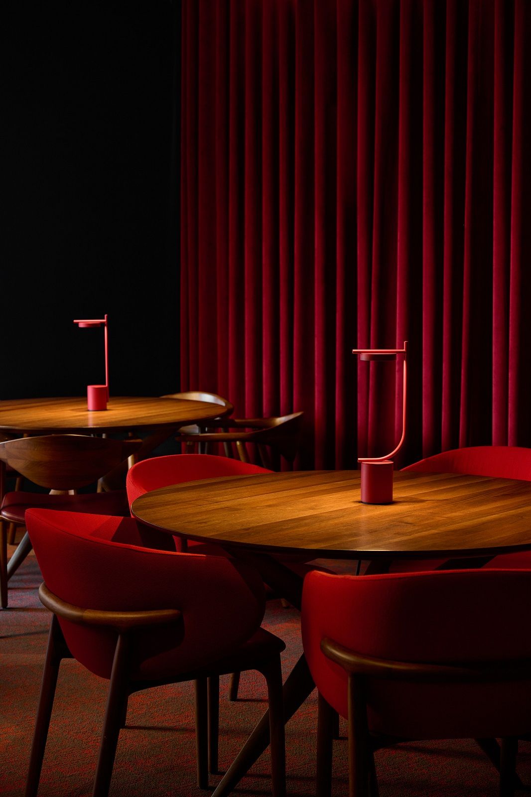 Rote Igram Tischleuchte von Grupa auf Holztisch in Restaurant mit roten Stühlen.