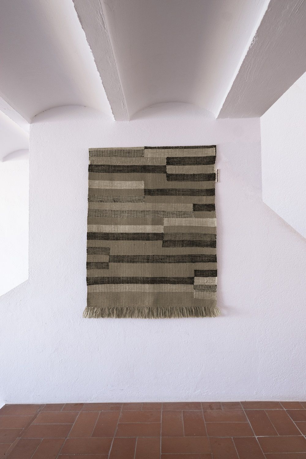 Nanimarquina Improvisation Tapestry: Wandteppich mit horizontalen Streifen in Braun- und Beigetönen, Fransen am unteren Rand.