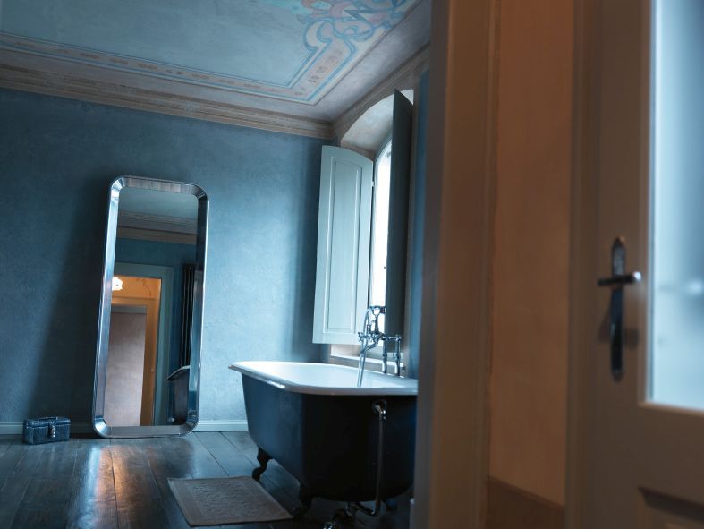 Badezimmer mit freistehender Badewanne und dem schlanken, silberfarbenen Deja-vu Spiegel von Magis an der Wand.