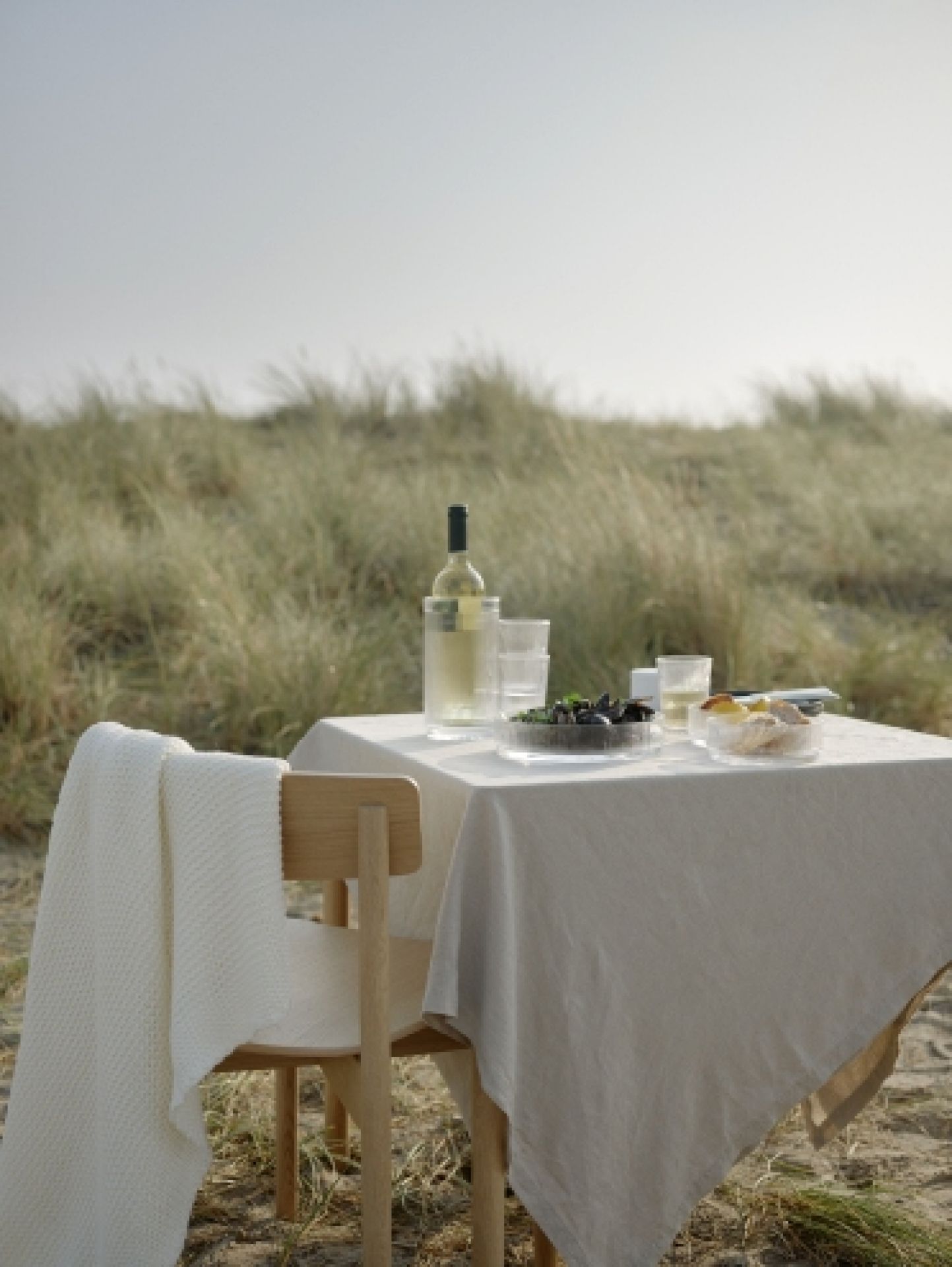 Pilastro Servierschale klein von Stelton auf gedecktem Tisch im Freien. Elegante Schale für Snacks und Dips.