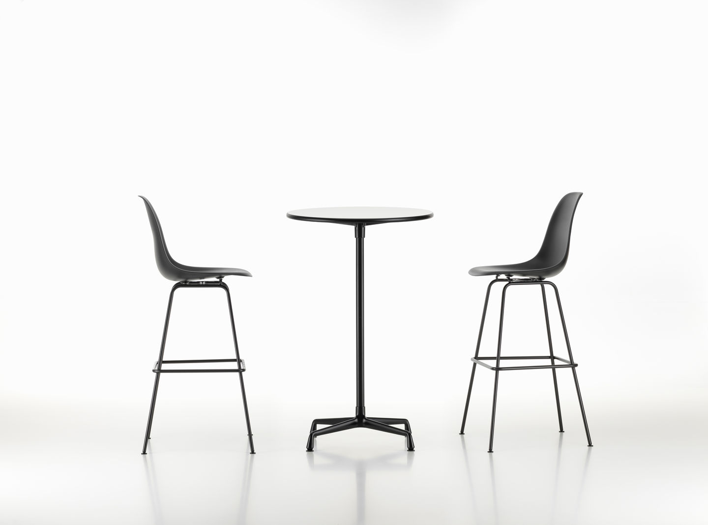 Zwei schwarze Eames Plastic Bar Stools von Vitra an einem Stehtisch auf weißem Grund.