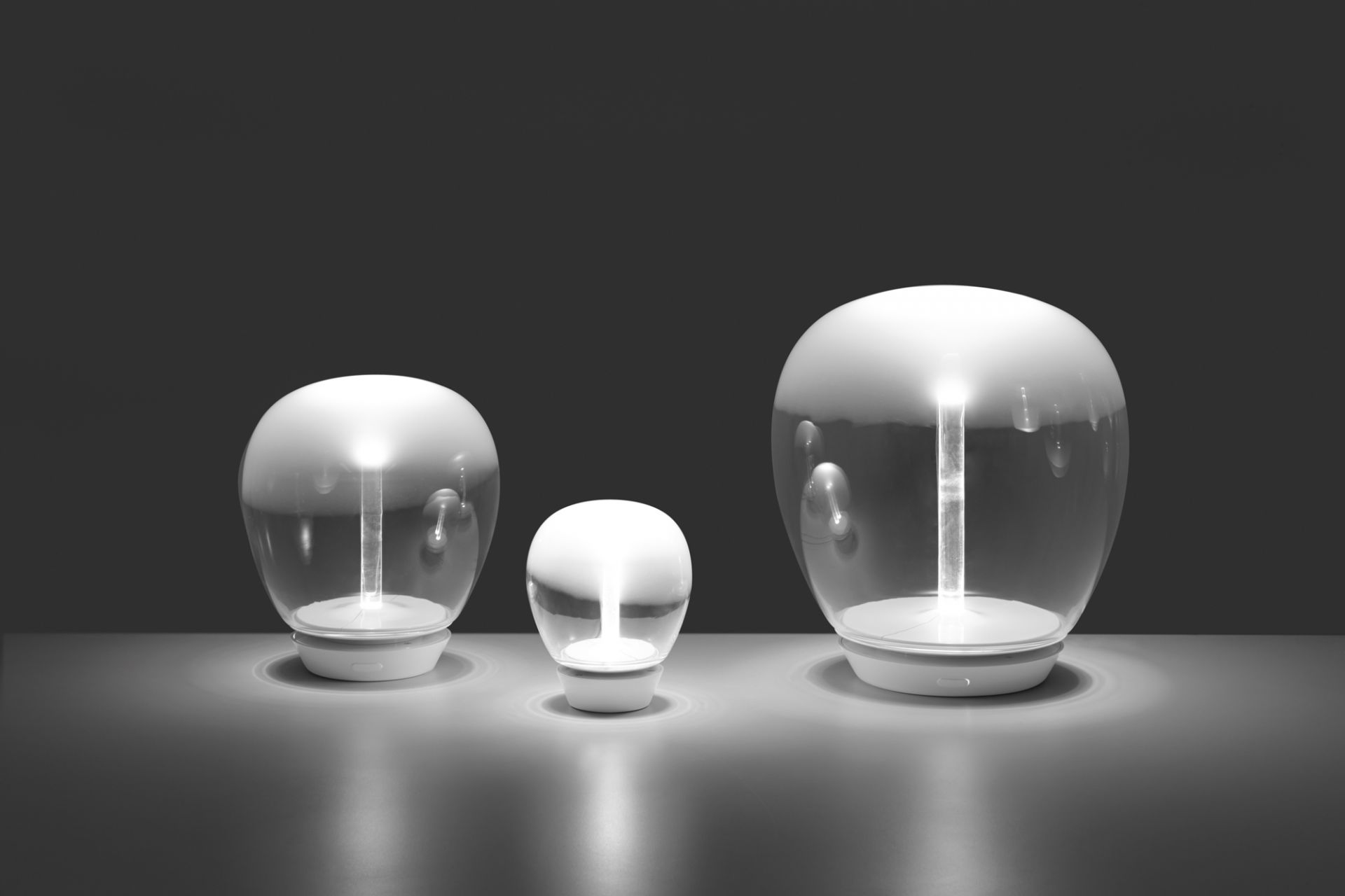 Drei Artemide Empatia Tischleuchten in verschiedenen Größen, modernes Design, stimmungsvolle Beleuchtung.