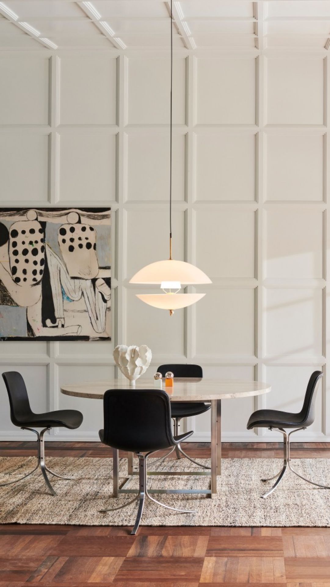 Clam Pendelleuchte von Fritz Hansen über Esstisch mit Stühlen und Kunstwerk im Hintergrund.