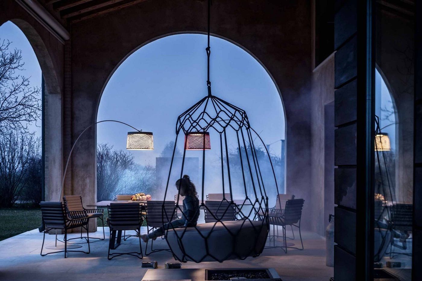 Twiggy Grid Stehleuchte kaminrot von Foscarini beleuchtet Terrasse mit Hängesessel und Esstisch.