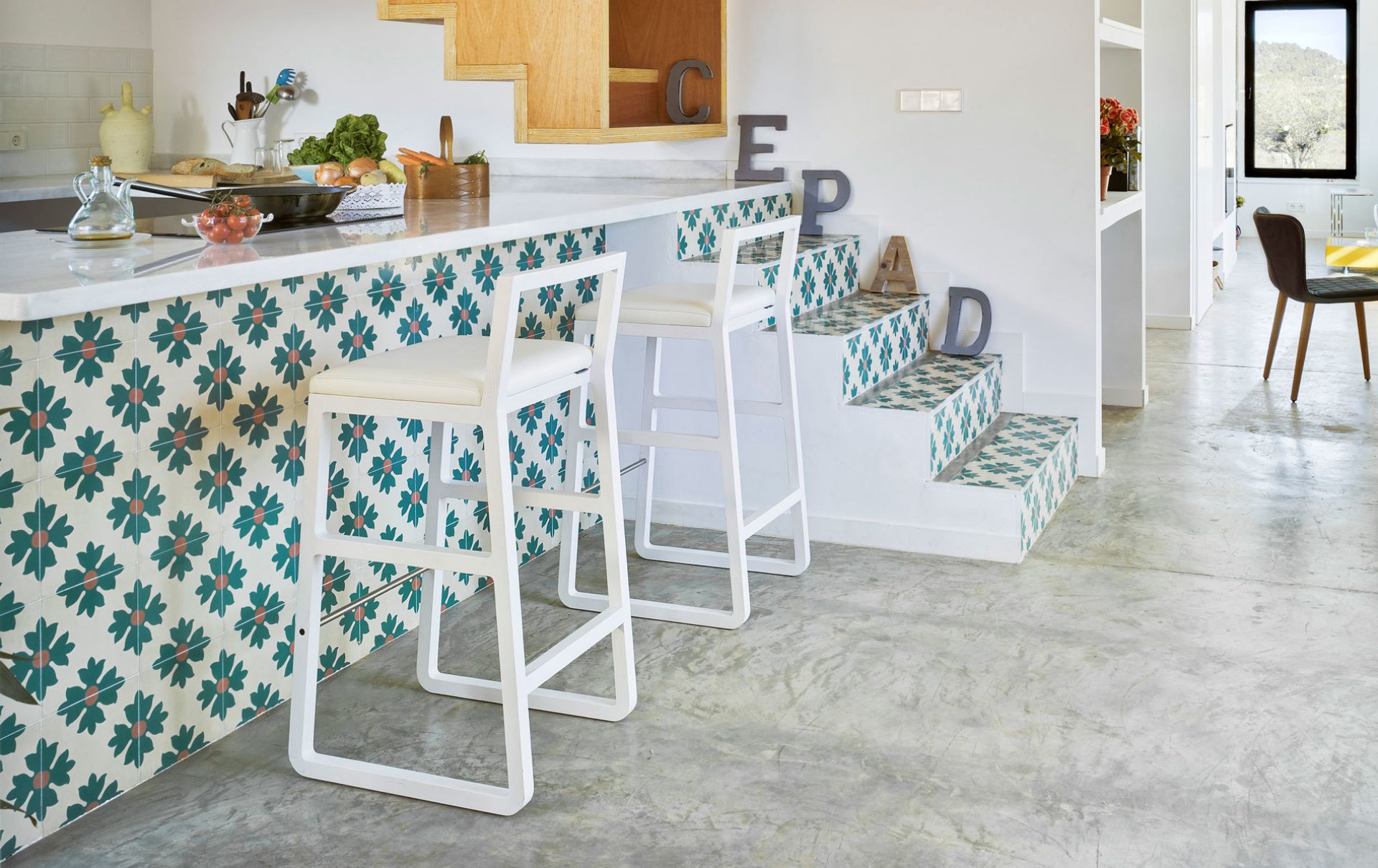 Zwei weiße Midori Hocker von Sancal an einer Küchentheke mit floralen Fliesen.