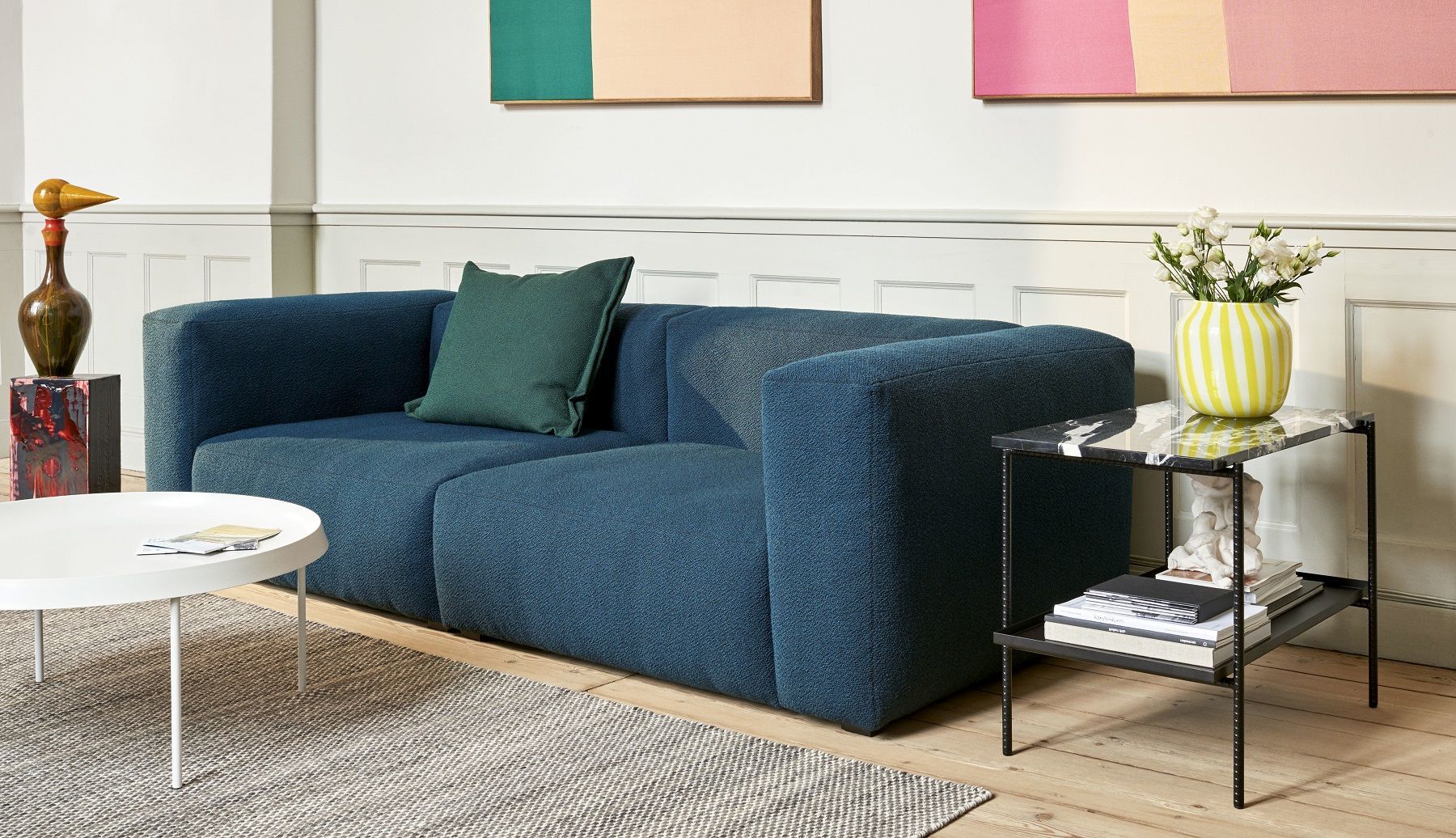 Hay Rebar Beistelltisch mit Marmorplatte und schwarzem Gestell neben blauem Sofa im Wohnzimmer.