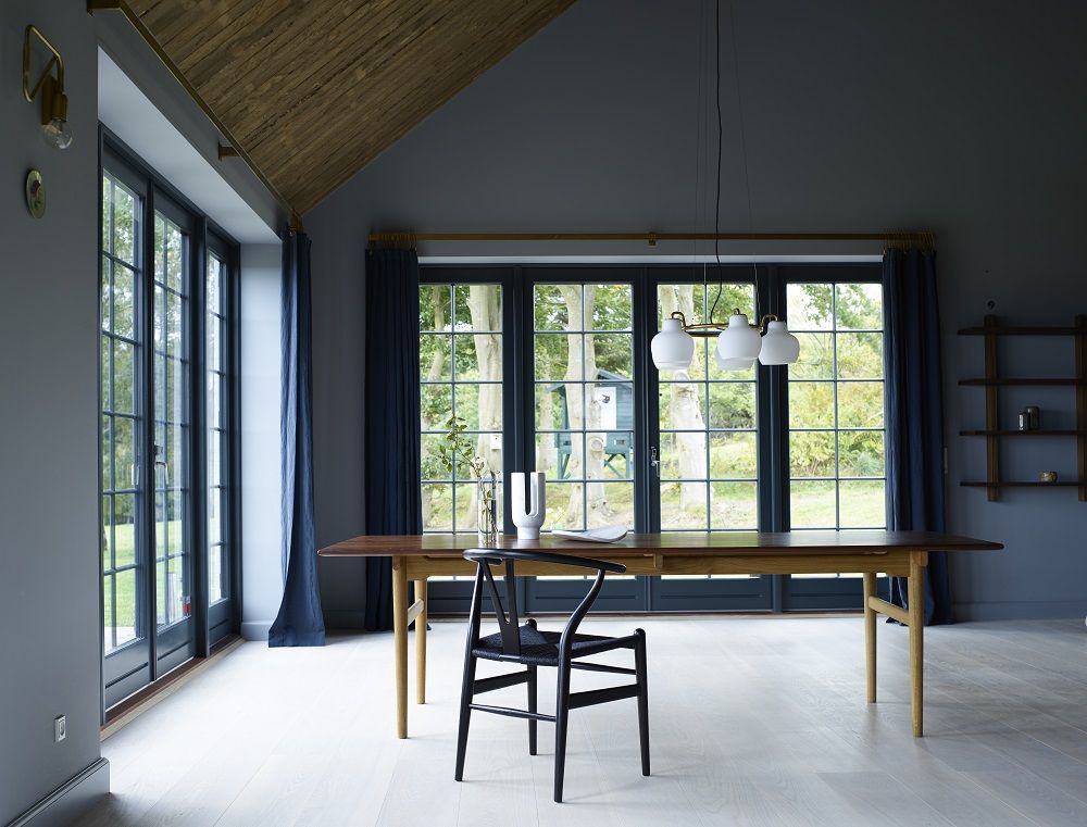 CH24 Wishbone Chair Stuhl in Schwarz vor Esstisch und Fenster, Carl Hansen Design.