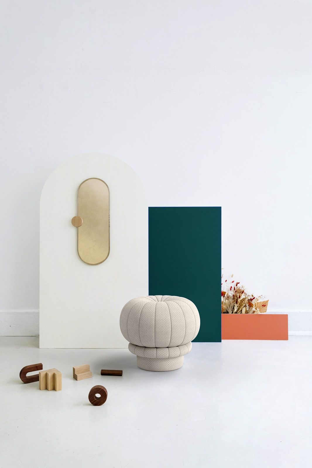 Beiger Claudie Pouf Hocker von Hartô, gepolstert, vor farbigen geometrischen Formen und Holzspielzeug.