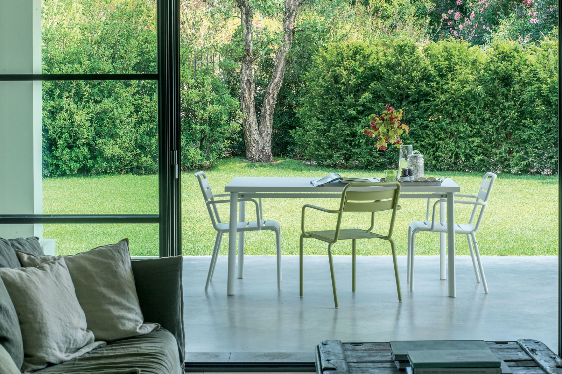 Gartenszene mit weißen und grünem Emu Star Stuhl und Tisch auf einer Terrasse.