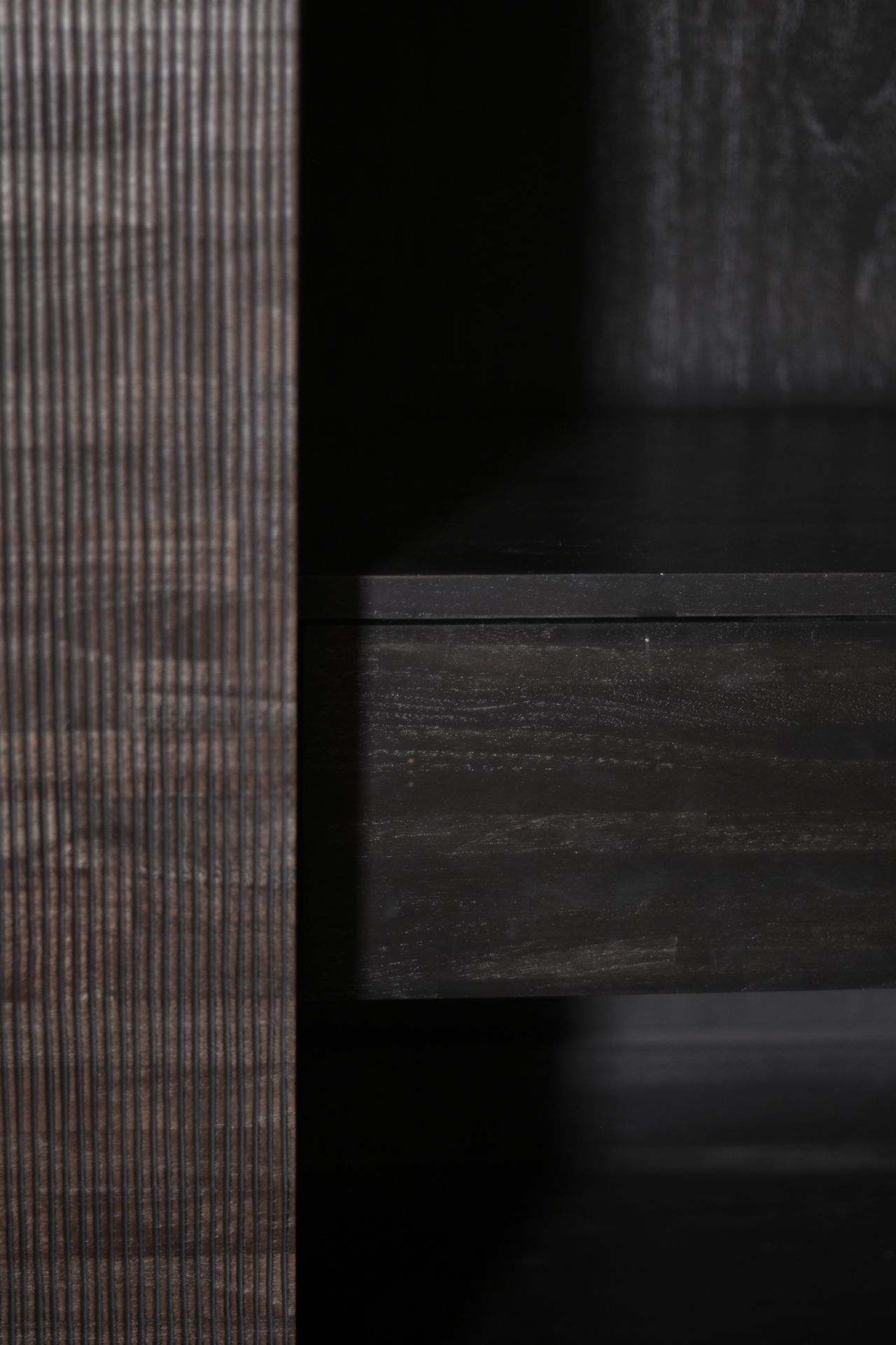 Detailaufnahme des Ethnicraft Teak Grooves Schrankes: Schublade und geriffelte Teakholz-Oberfläche in dunkler Ausführung.