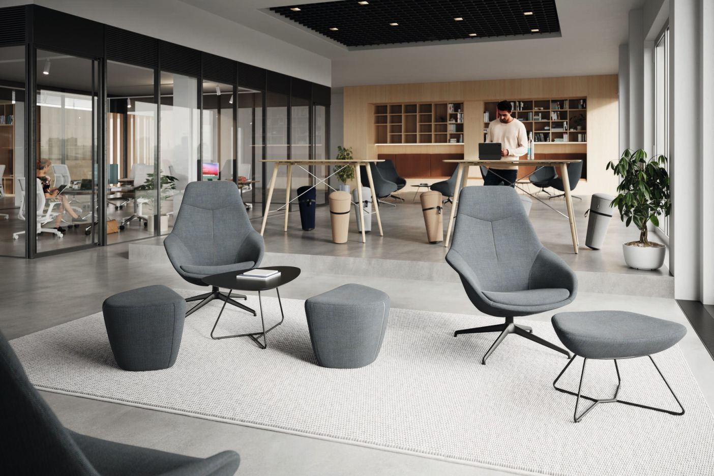 Graue Yonda Ottoman von Wilkhahn in modernem Büro, mit passendem Hocker und kleinem Tisch.