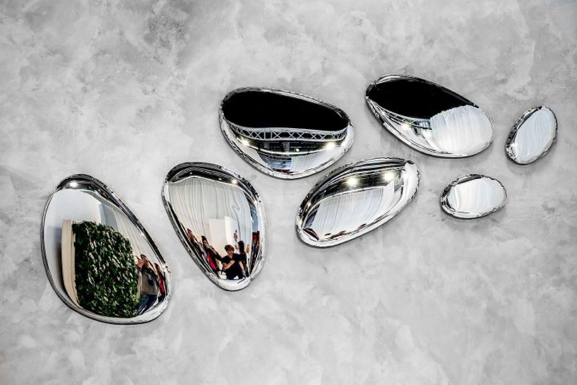 Tafla Spiegel von Zieta: Mehrere ovale, silberne Design-Spiegel an einer grauen Wand.