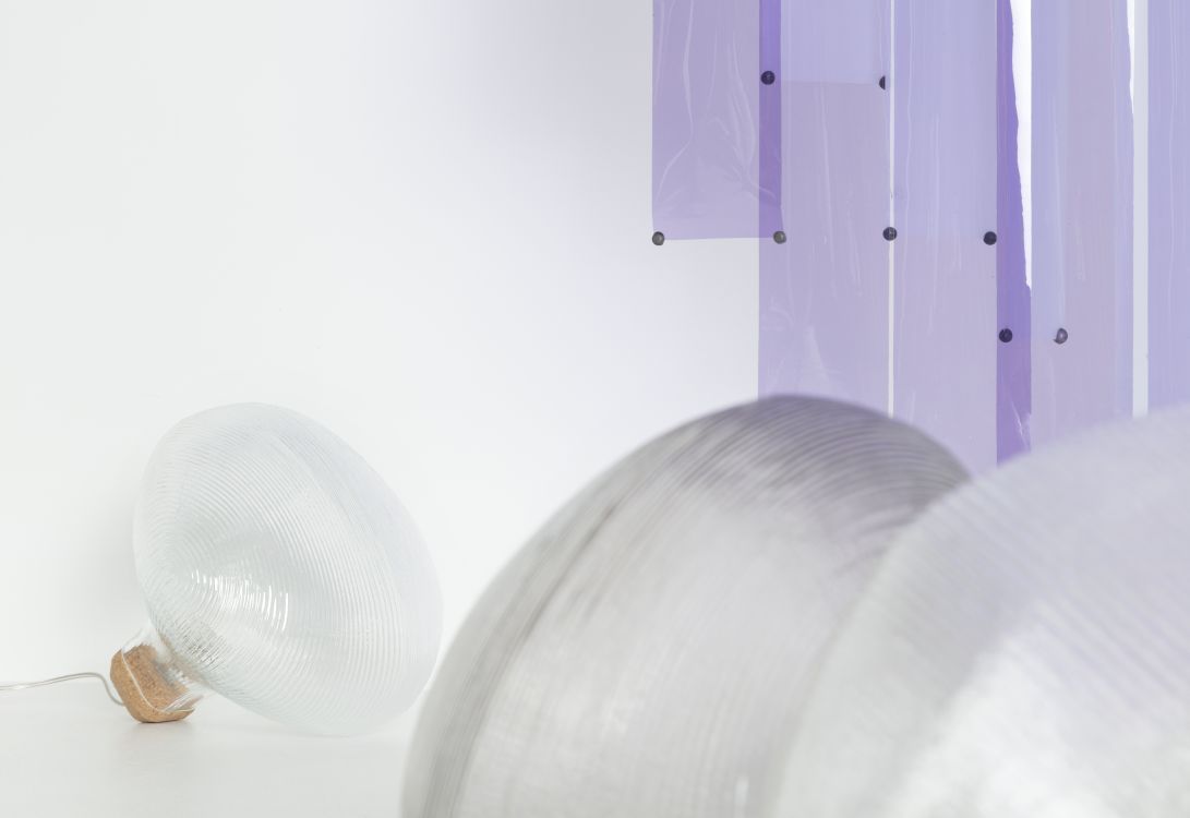 Tidelight Tischleuchte von Petite Friture, moderne Lampe mit geripptem Glasschirm und Korkfuß auf weißem Untergrund.