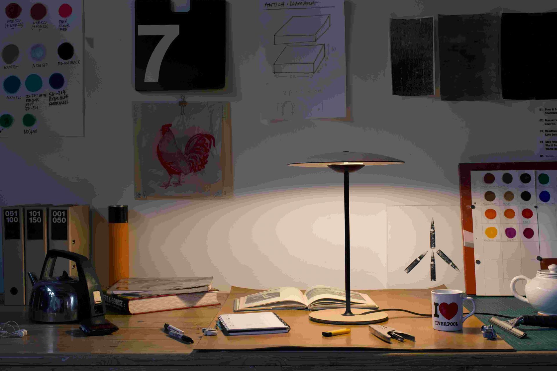 Ginger M LED Tischleuchte von Marset auf einem Schreibtisch mit Büchern und Accessoires.