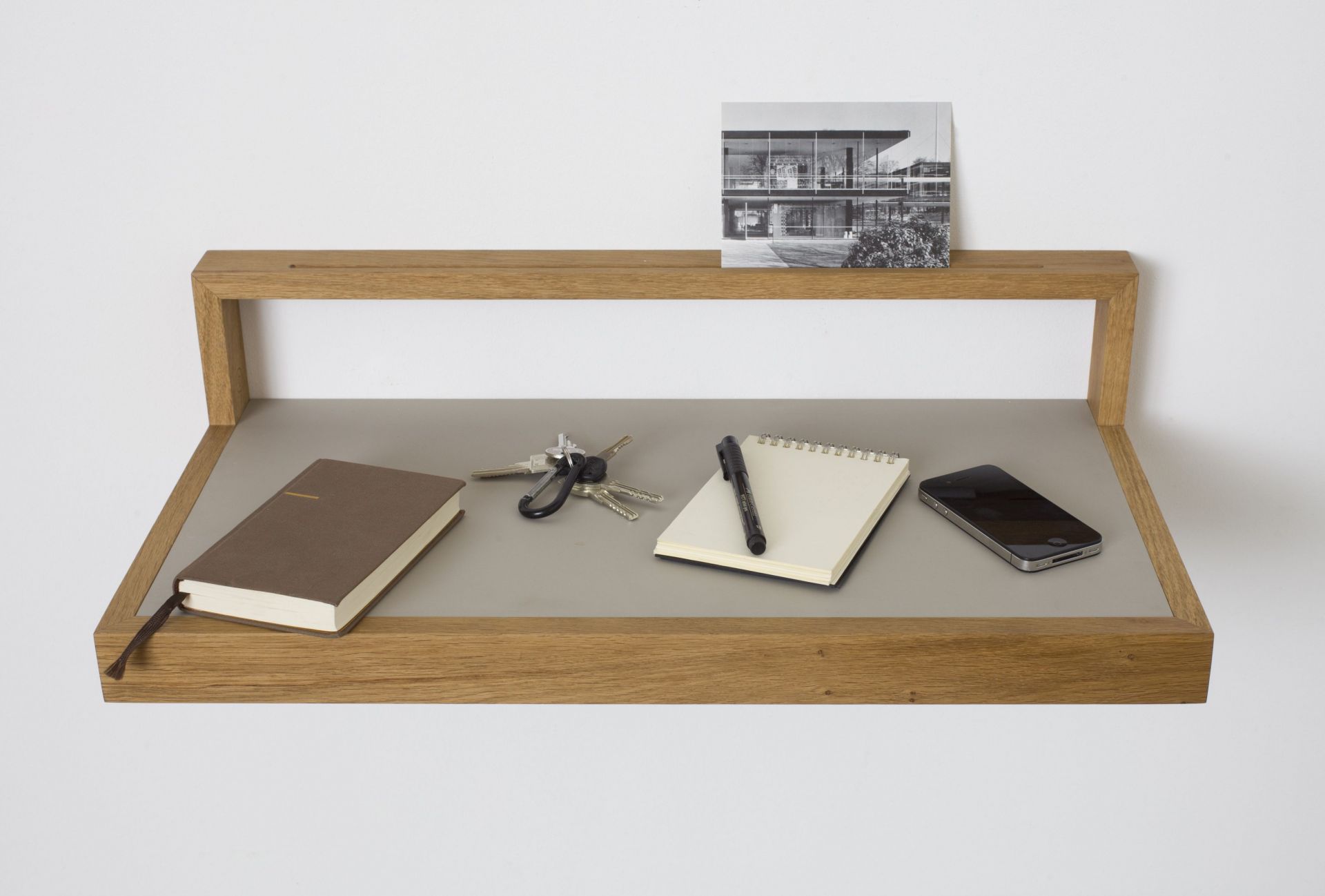 Hellgraues Ablageboard "buck1" mit Notizbuch, Stift, Handy und Schlüssel. Wandregal aus Holz für Büro und Zuhause.