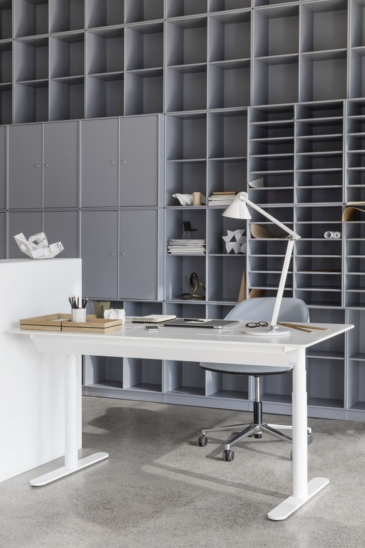 Weißer HiLow Arbeitstisch mit Schiebeplatte von Montana, höhenverstellbar, im modernen Büro mit Regalen.