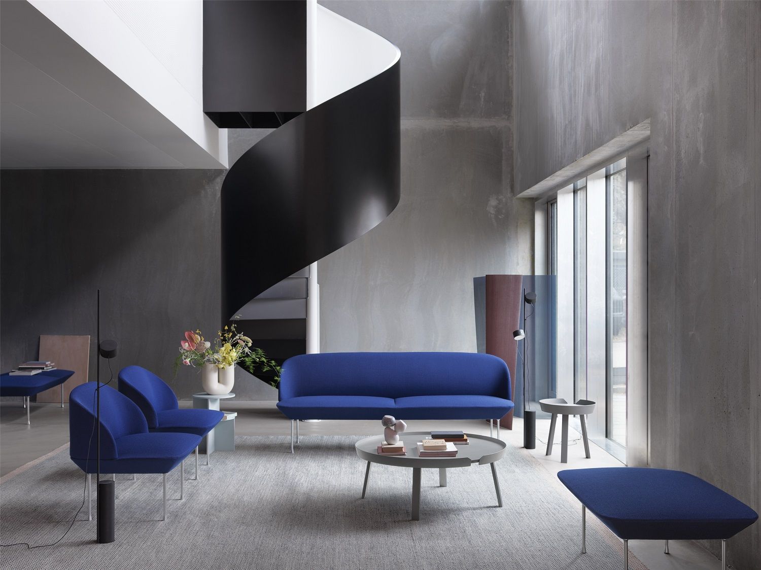 Blauer Oslo Pouf Hocker von Muuto in modernem Wohnzimmer mit Sofa und Sesseln.