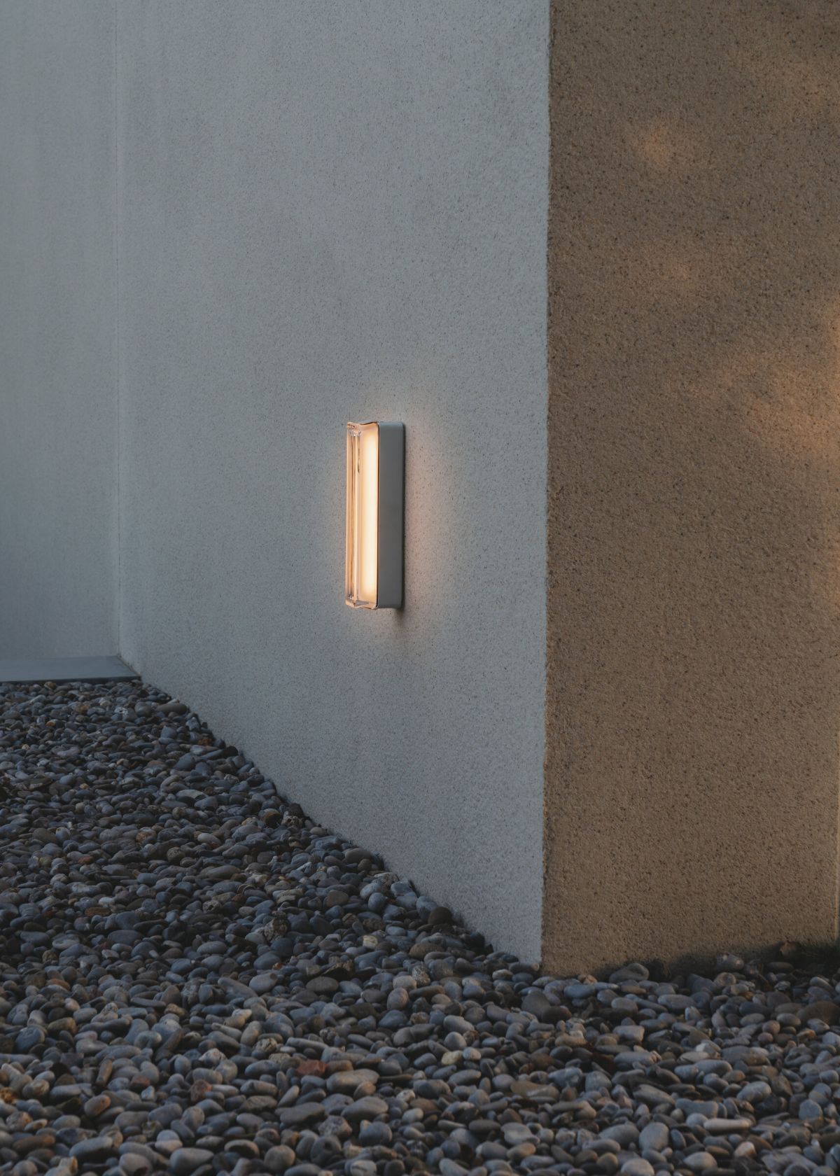 Weiße Estadio Singluar Wandleuchte von Santa & Cole an einer Fassade, Außenbeleuchtung.