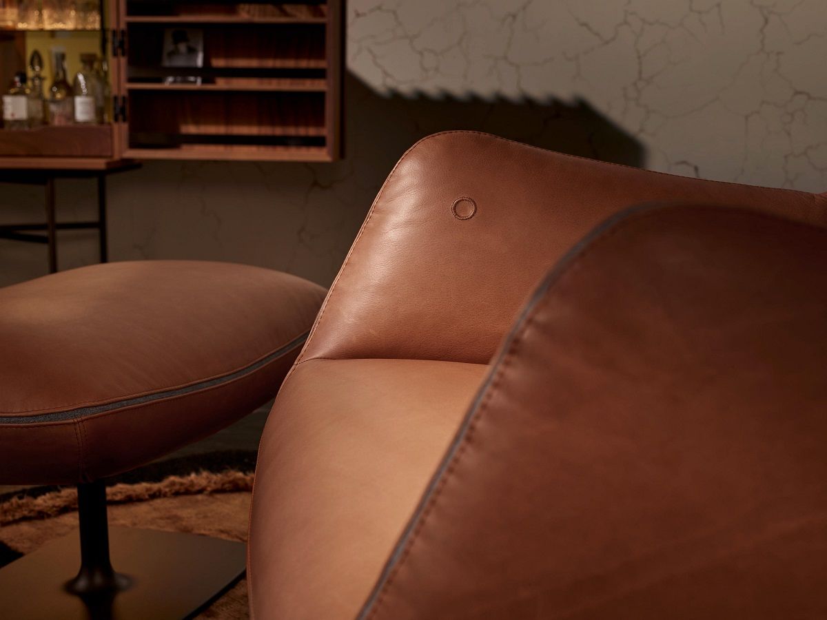 Nahaufnahme: Brauner Jalis Lounge Sessel mit Hocker, Leder, Tellerfuß und Kippmechanik.
