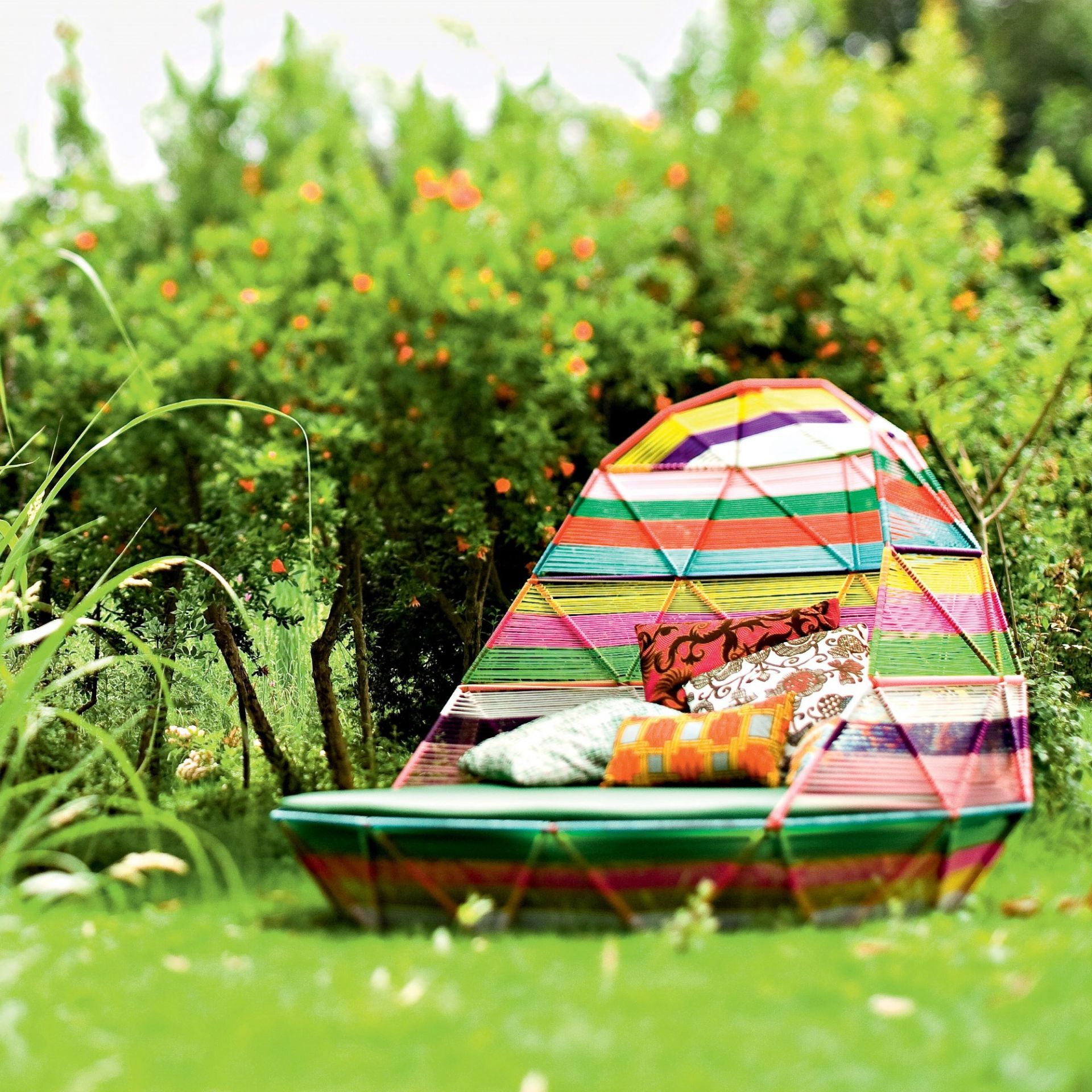 Farbenfrohe Tropicalia Day Bed Liege von Moroso im Garten mit Kissen und grüner Natur.