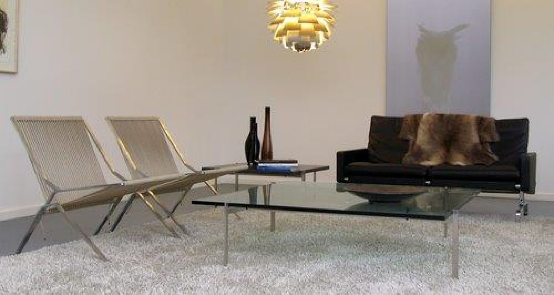 Zwei PK25 Sessel von Fritz Hansen im Wohnzimmer mit Sofa und Glastisch.