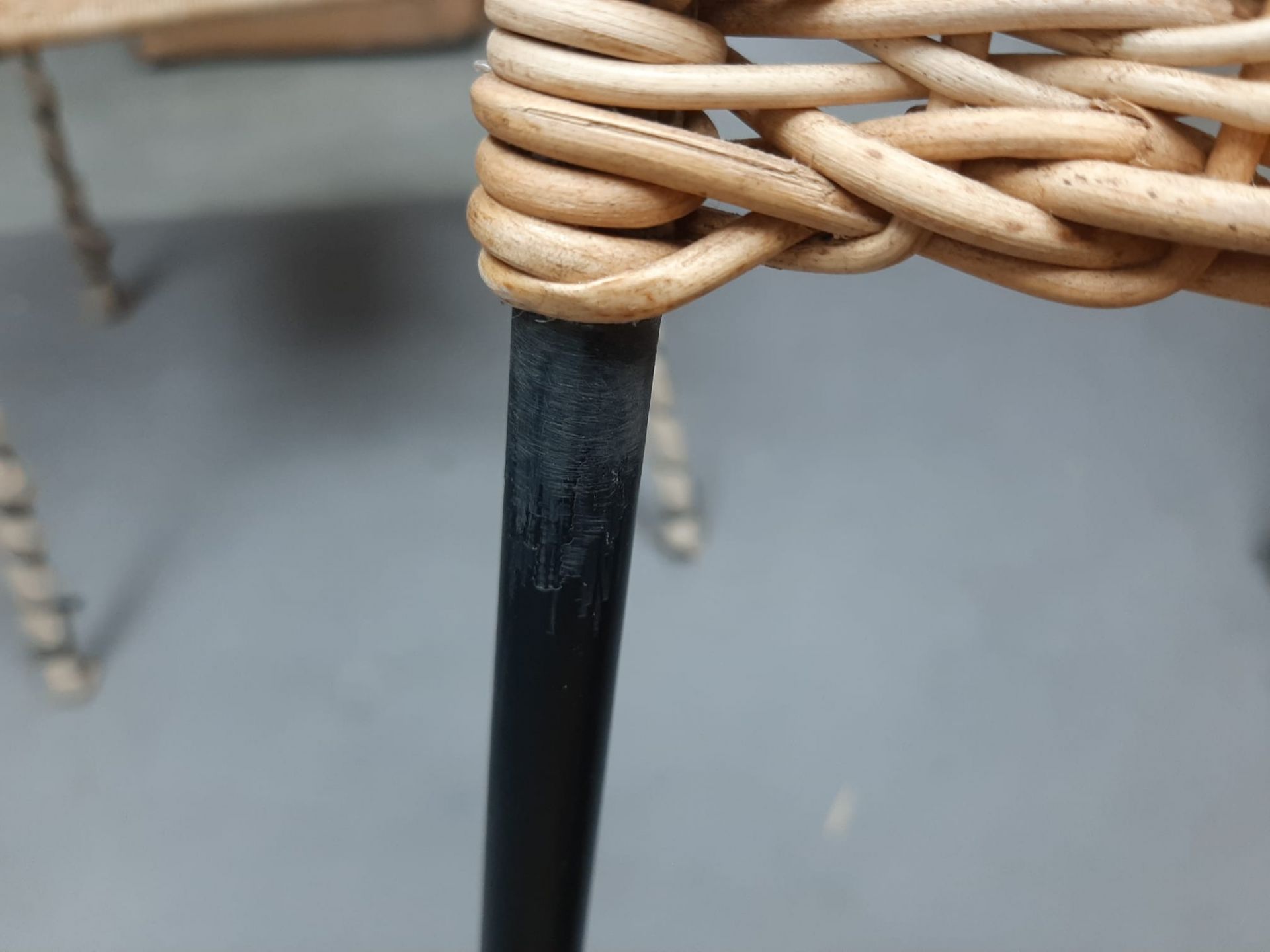 Detailaufnahme Stuhl TT 54 (Mängelexemplar): Geflochtene Sitzfläche aus Rattan, schwarzes Metallbein mit Lackschäden.