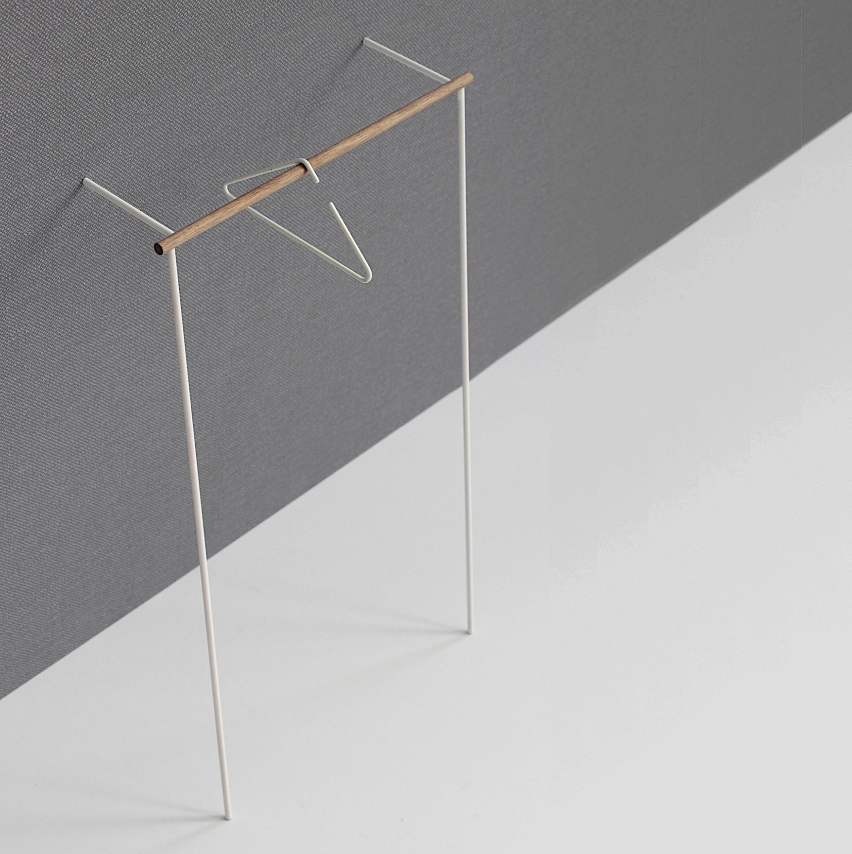 Weiße Leanon II Anlehngarderobe von Roomsafari mit Holzakzent und Kleiderbügel vor grauer Wand. Moderne Garderobenlösung.