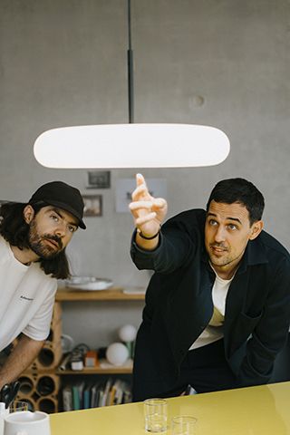 Zwei Männer unter der Oto Pendelleuchte von Belux. Moderne, schwarze Hängelampe für Wohnraumbeleuchtung.