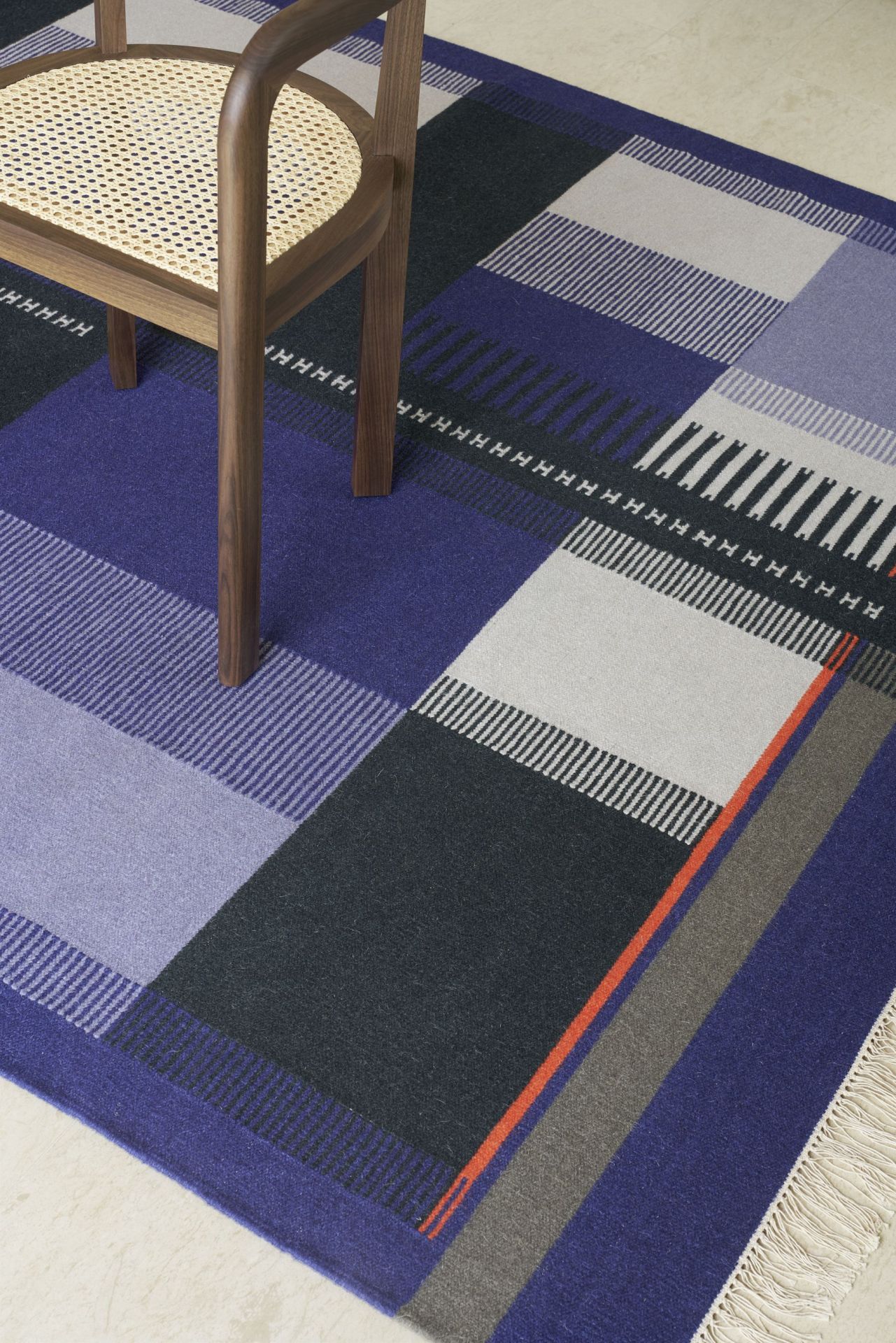 RH01 Stuttgart Stuhl e15 aus Holz mit Rattan Sitz auf gemustertem Teppich.