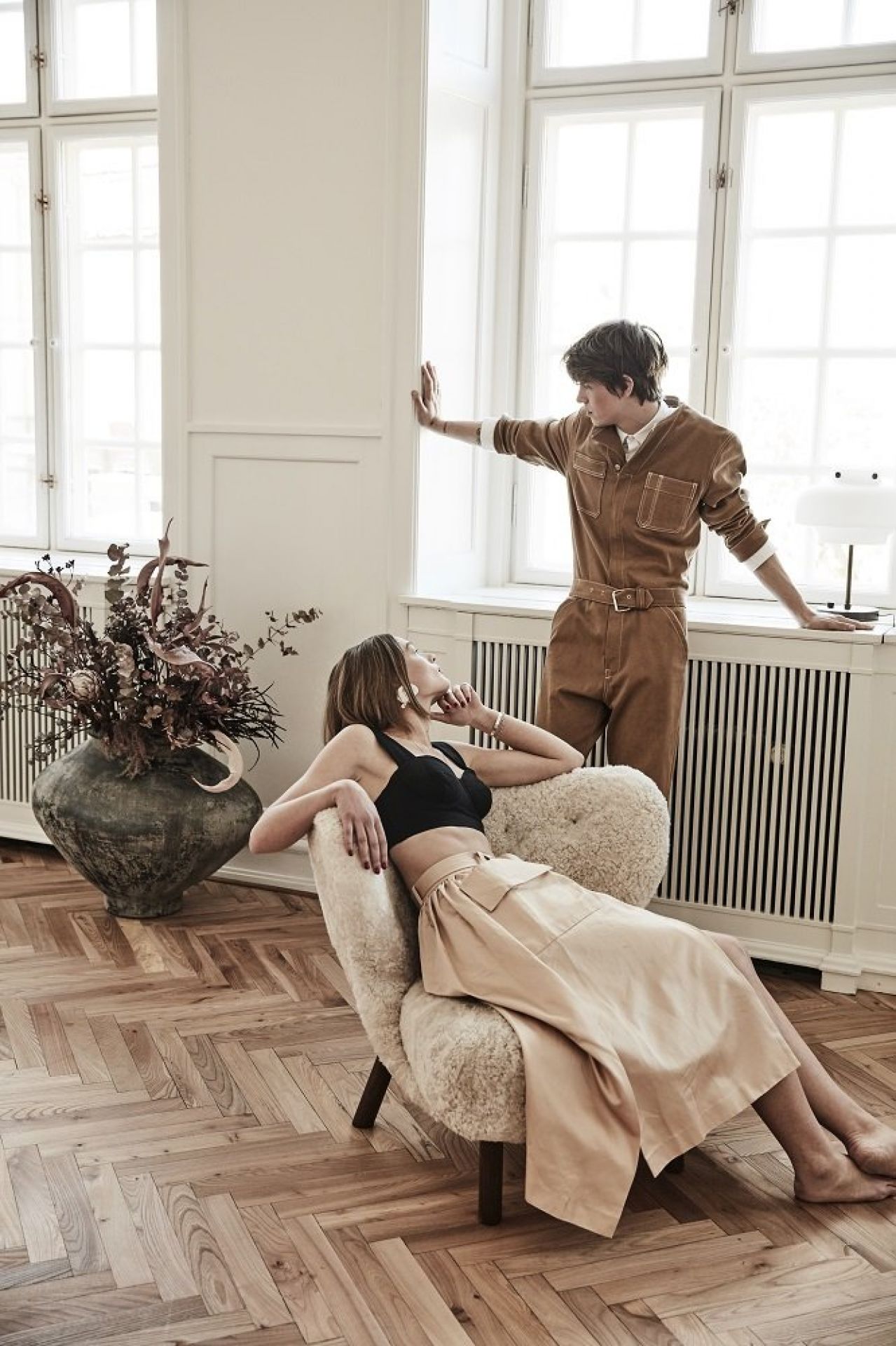 Frau entspannt im Little Petra Sessel von &Tradition, Walnuss-Gestell, Moonlight-Bezug. Gemütlicher Lounge Sessel.