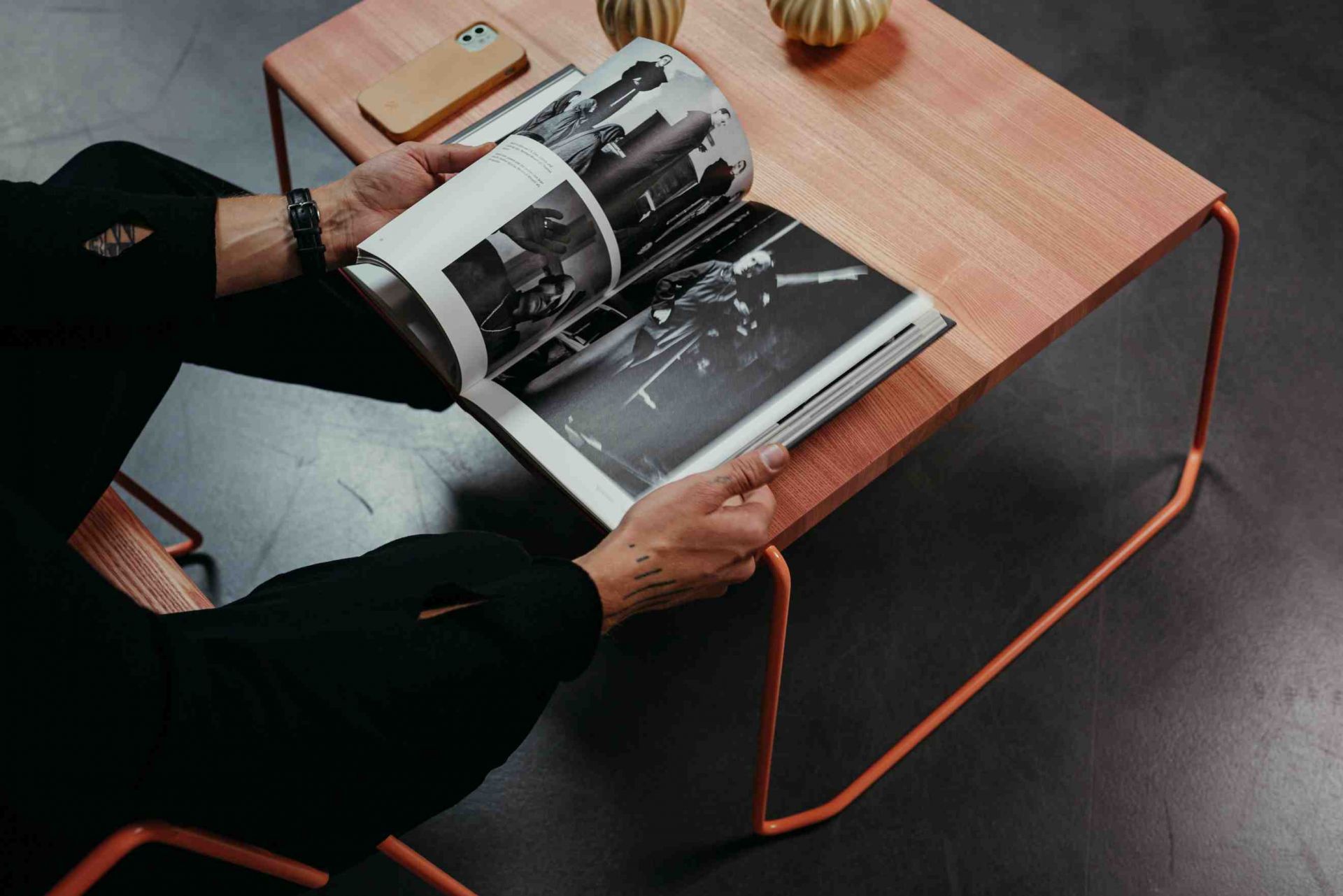 Mann liest Zeitschrift am D:009 Coffeetable Fuchs & Habicht mit Holzplatte und Metallgestell.