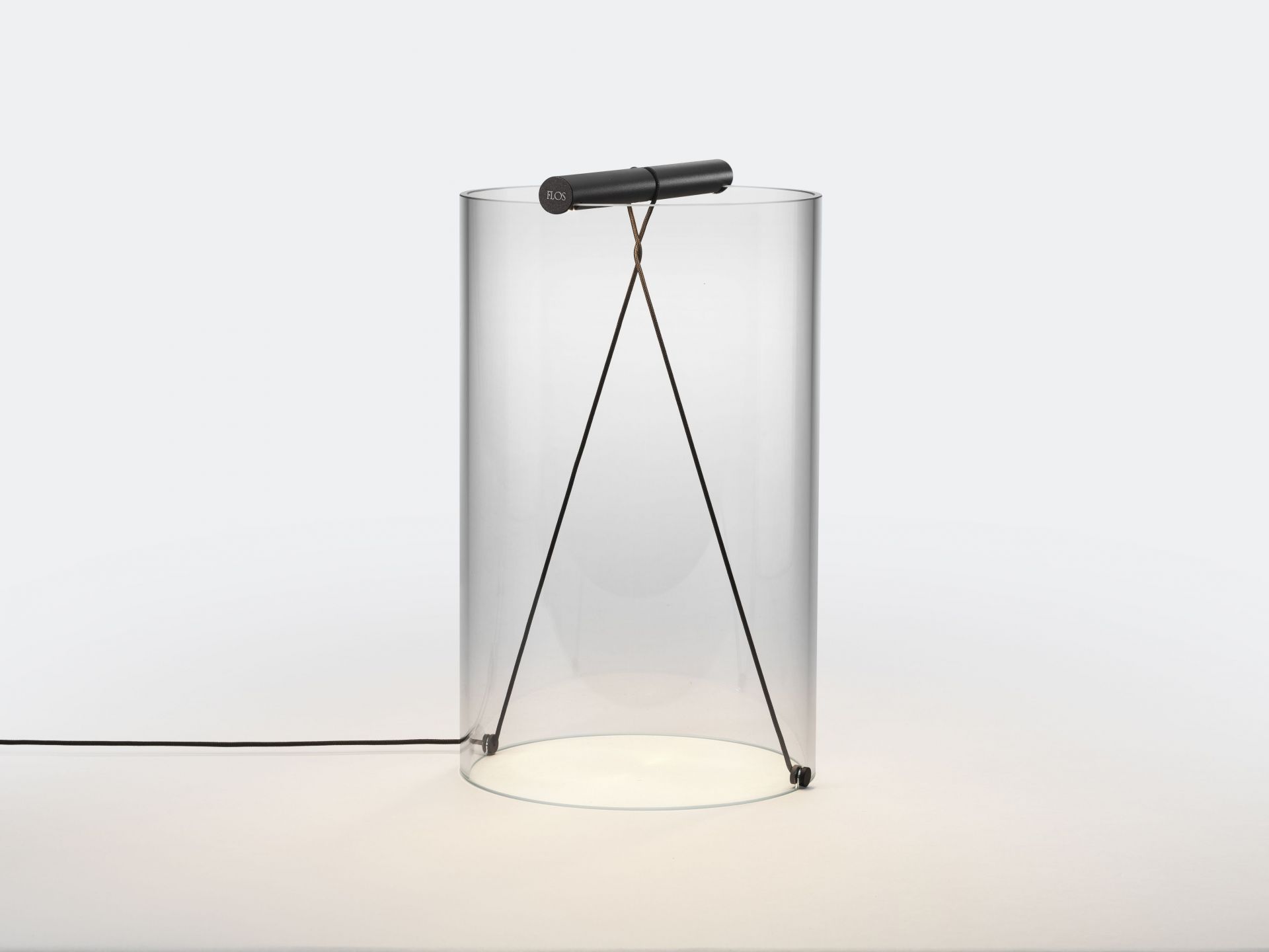 To-Tie T2 LED Tischleuchte von Flos, schwarzer Stab über transparentem Zylinder mit Kabeln.