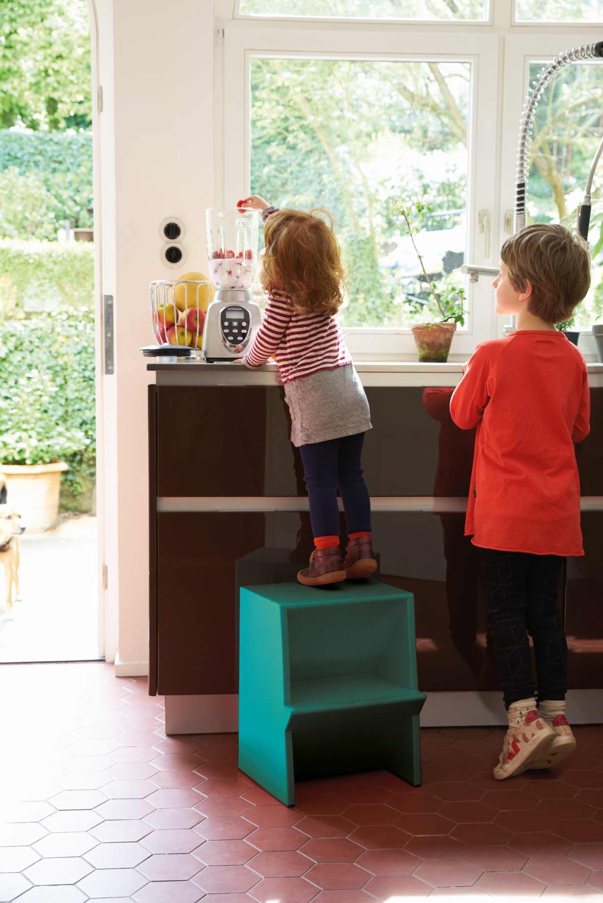 Mädchen auf türkisem Tritthocker von Richard Lampert, um an den Mixer zu gelangen.