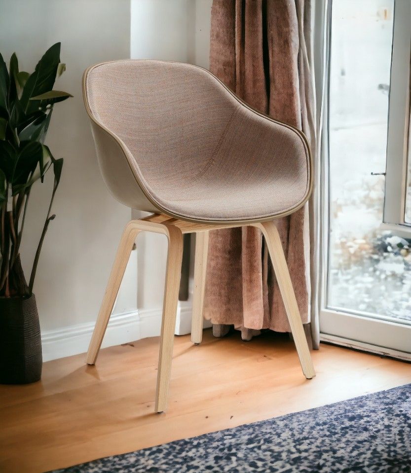 About A Chair AAC222 Stuhl mit Eichengestell und beigem Stoffbezug vor Fenster.