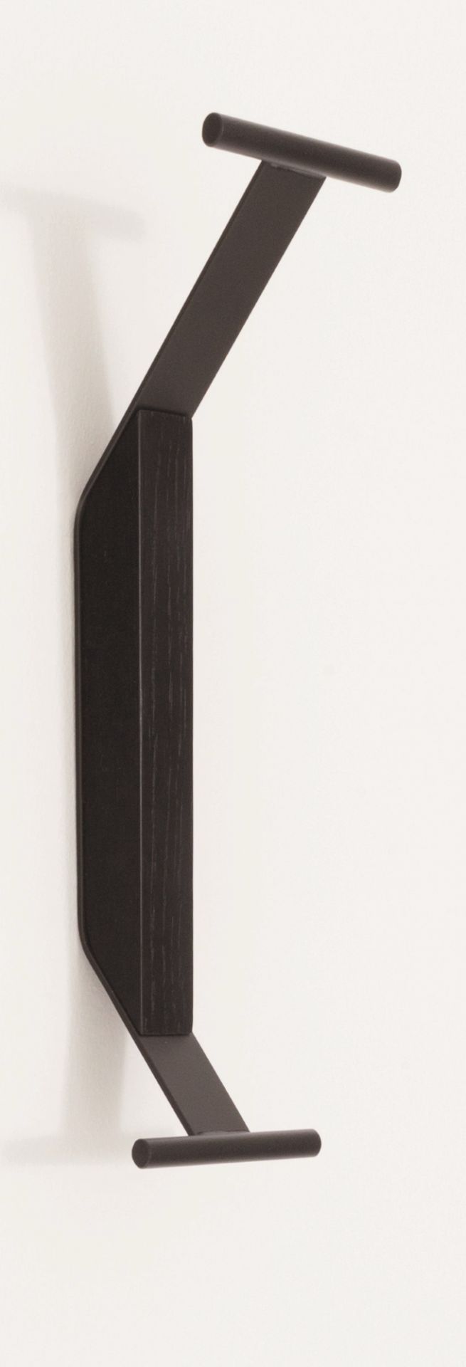 Schwarzer Artek Kaari Wandhaken REB 014 aus Holz und Metall an einer weißen Wand.
