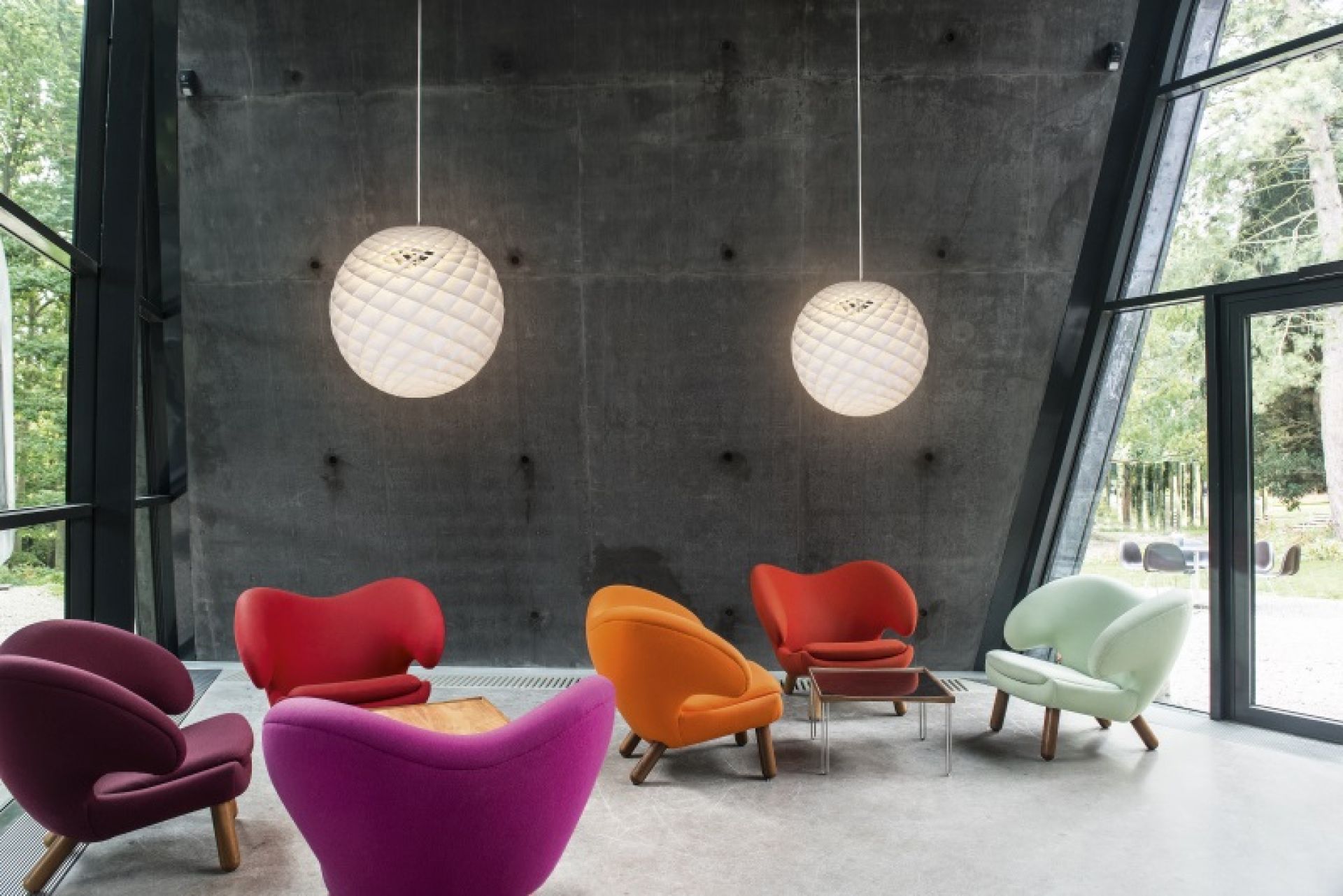 Zwei Patera Pendelleuchten von Louis Poulsen in modernem Raum mit bunten Sesseln.