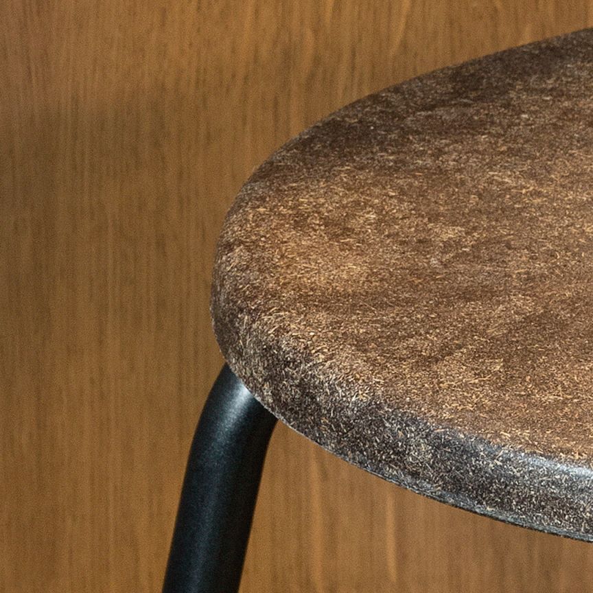 Detailaufnahme: Sitzfläche des Earth Stool Barhockers in dunklem Braun mit schwarzem Gestell.