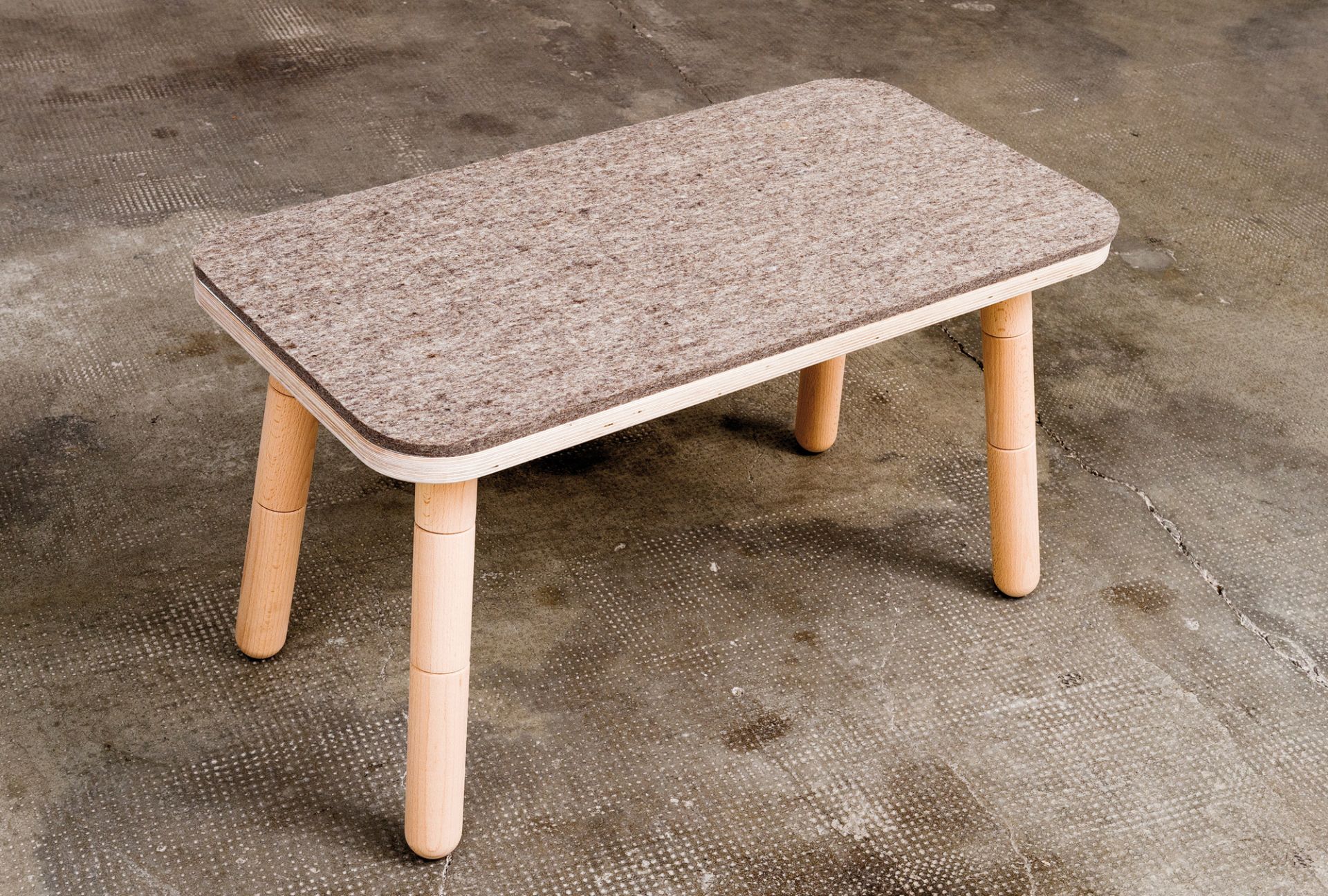 Growing Table: Bank Pure Position Sitzfilzauflage aus Filz auf Holztisch mit hellen Holzbeinen.