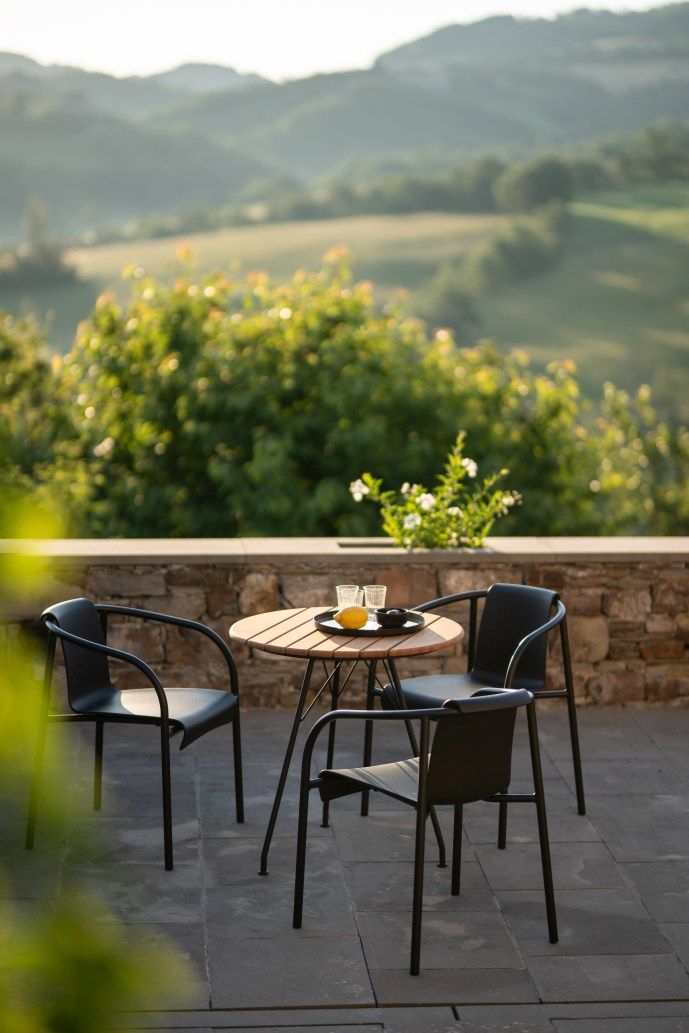 Nami Armlehnstuhl von Houe für den Außenbereich mit Tisch und malerischer Landschaft.