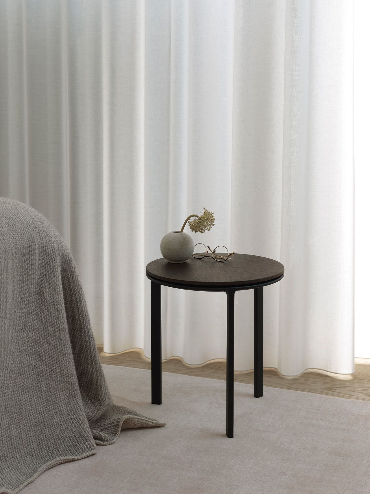 Vipp Beistelltisch mit runder Tischplatte und schwarzem Gestell, dekoriert mit Vase und Brille.