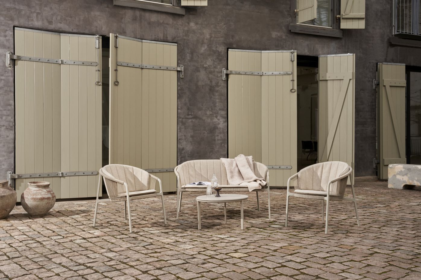 Lagrasse Zweisitzer Sofa von Vipp mit Outdoor-Stühlen und Tisch auf einer Terrasse. Gartenmöbel-Set.