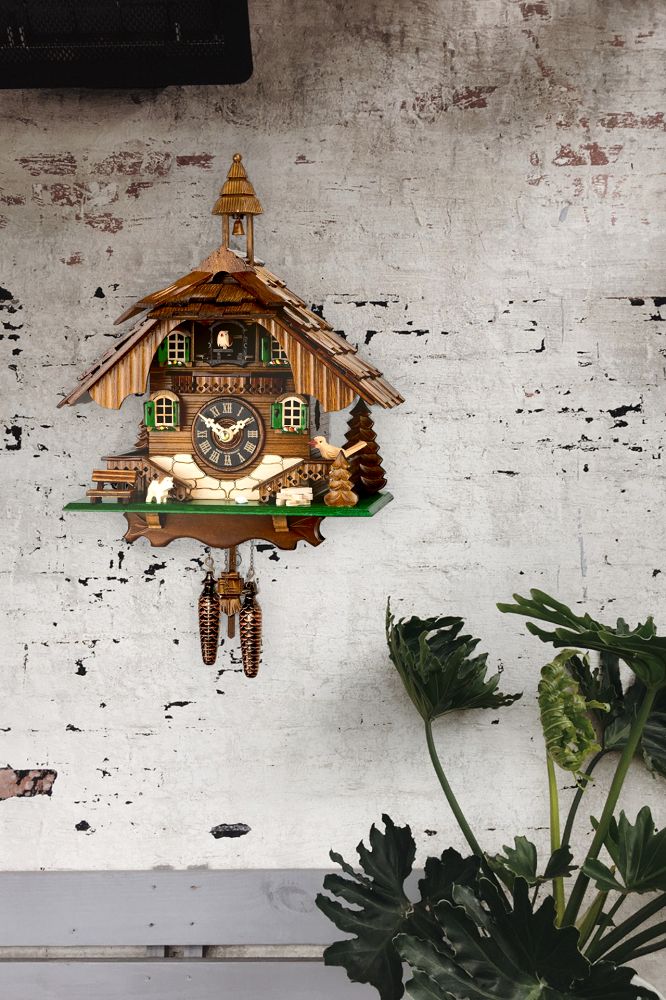 Detailaufnahme einer Engstler Kuckucksuhr mit Quarzwerk, traditionelles Schwarzwaldhaus-Design mit Pendel und Gewichten.