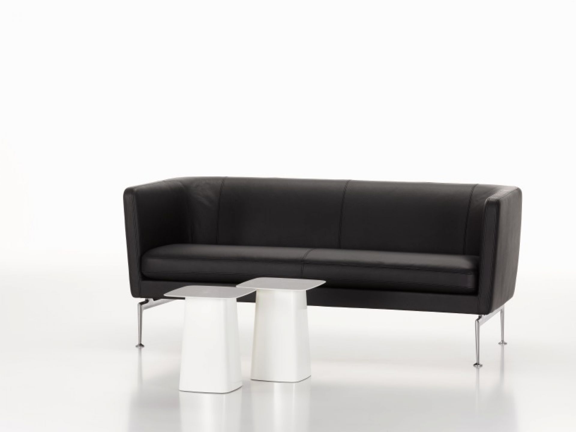 Schwarzes Suita Sofa von Vitra mit zwei weißen Beistelltischen auf weißem Hintergrund.