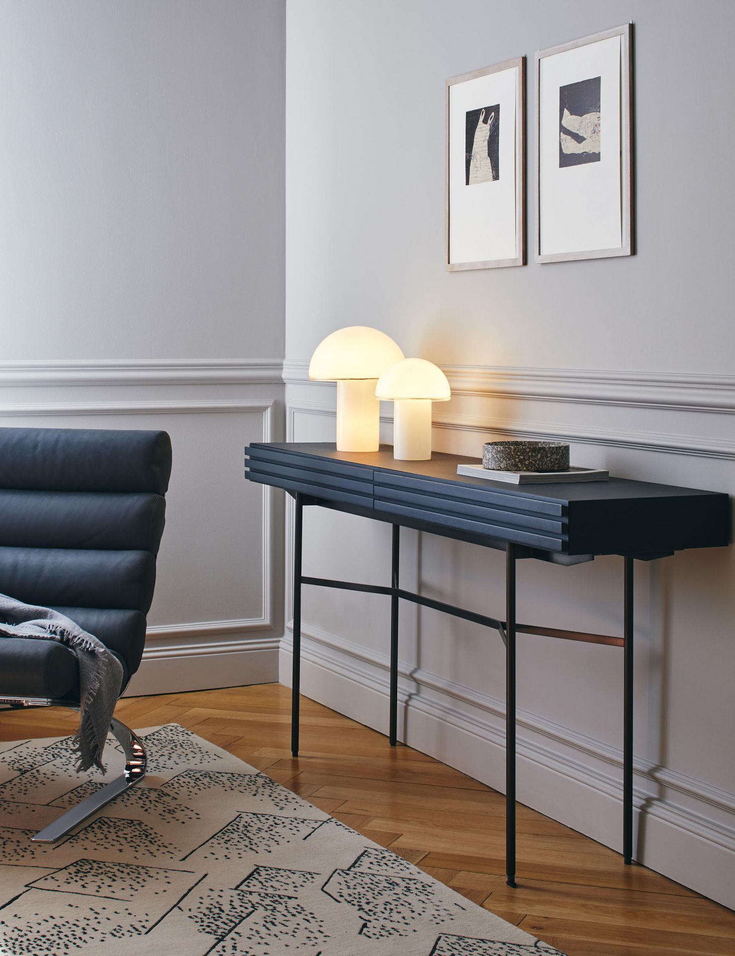 Zwei Onfale Tischleuchten von Artemide auf einem schwarzen Konsolentisch in einem stilvollen Interieur.